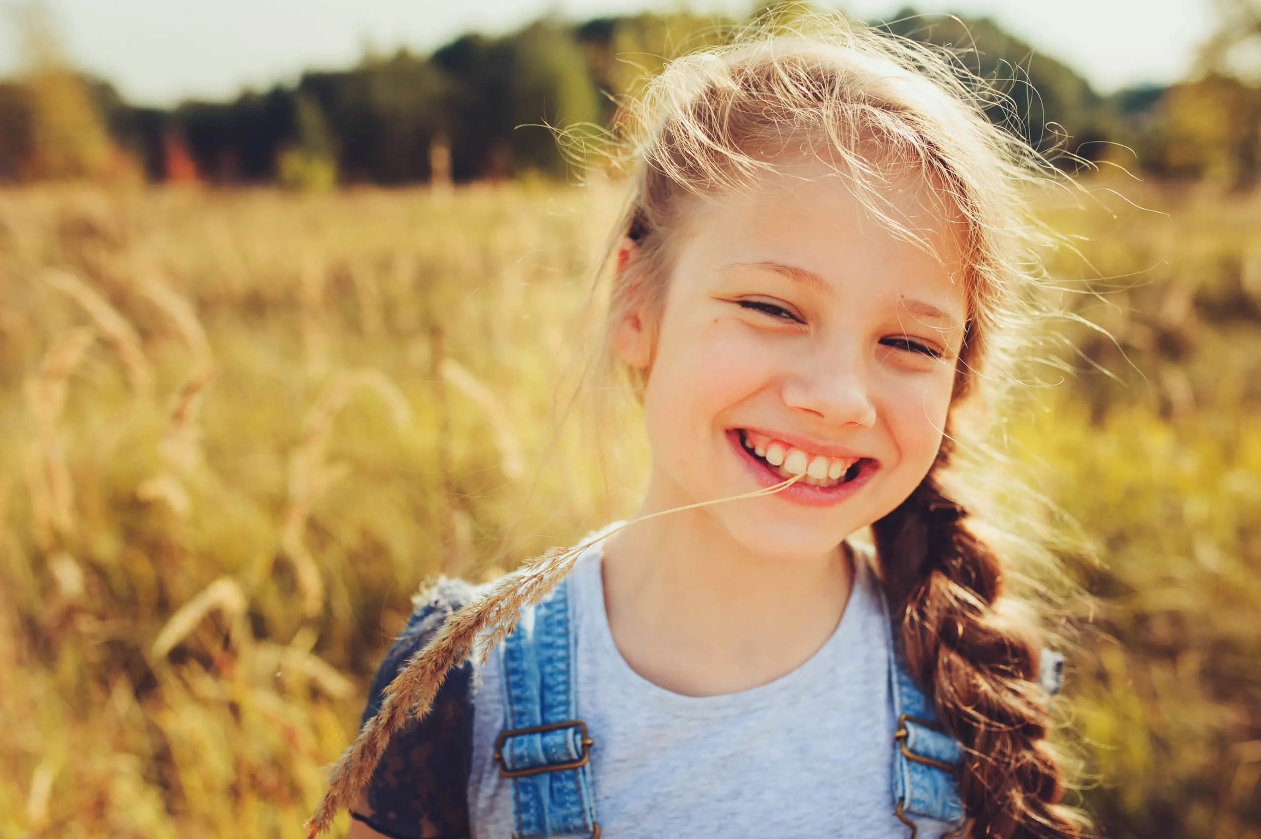 Happy,child,girl,in,jeans,overall,playing,on,sunny,field,